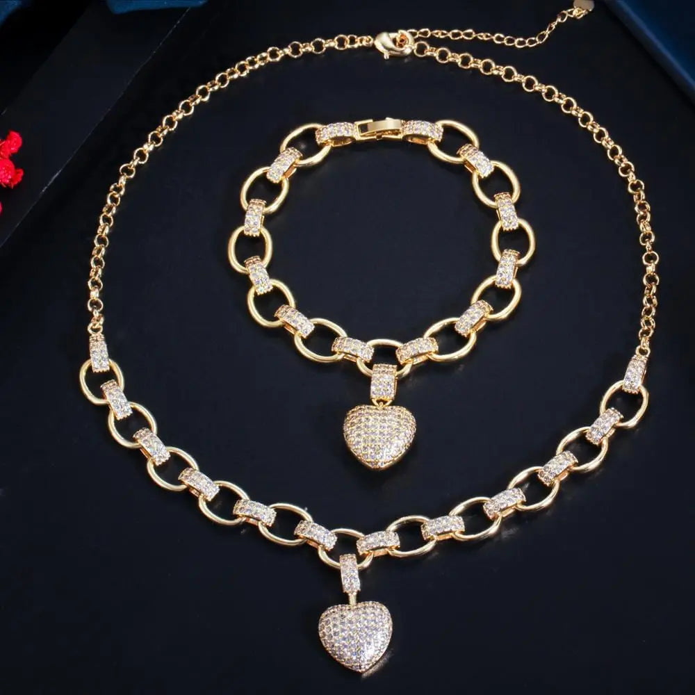 The CWWZircons 585 gold color cubic zirconia heart charm bracelet and necklace jewelry set (T468) features sparkling love heart pendants—an eye-catching jewelry set displayed on a black surface.