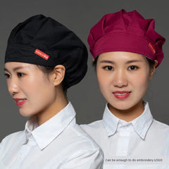 Two women wearing black and maroon chef caps with a small brand label on the side.