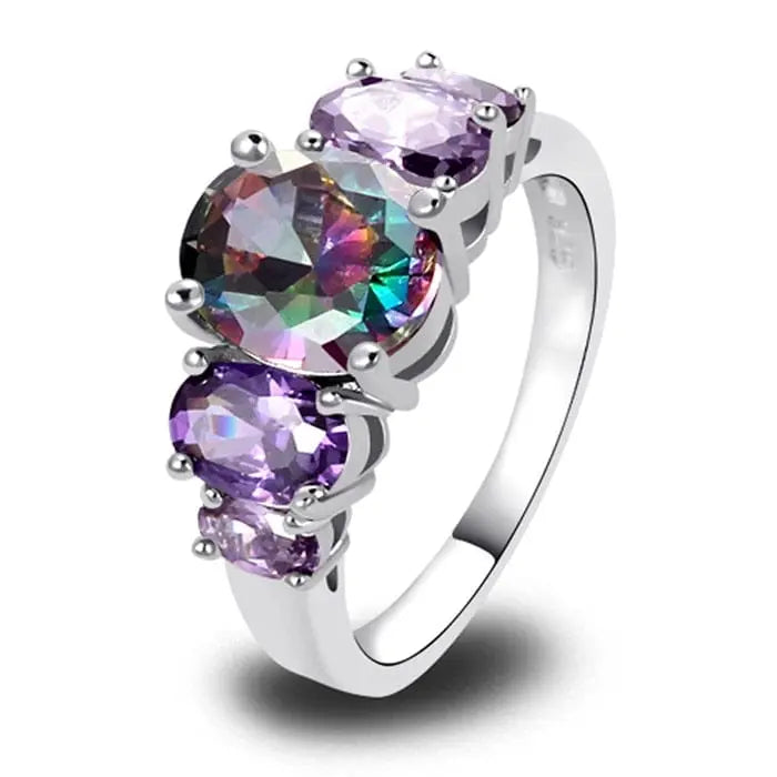 The CiNily Luxurious Mystery Stone Ring is a silver-plated fashion ring featuring a large rainbow topaz, flanked by two oval and two small round purple stones—an eye-catching accessory for women.