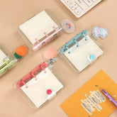 Three small, transparent three-ring mini binders with colorful accents sit on a desk.