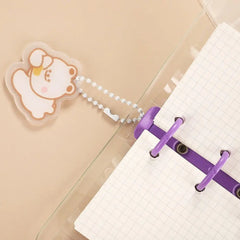 A transparent mini three-ring binder notebook featuring a cute bear charm on a beaded chain.