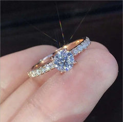 A delicate silver-colored ring featuring a round prong-set stone and a pavé-set band.