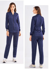 A woman wears a navy blue zip-up scrub jacket and matching pants from front and back views.