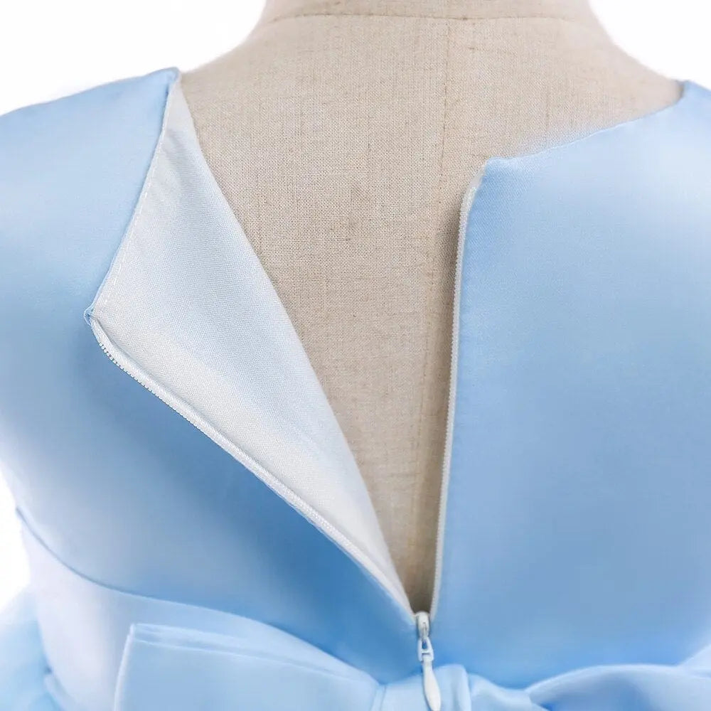 Close-up of the back of the Elegant Kids Dress For Girls Birthday Wedding Costume, showing light blue satin fabric, open zipper, large waist bow, and visible lining; ideal for girls aged 3-10 at parties or special occasions.