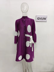 A mannequin displays the Elegant Stand Collar Pleated Dress, a purple long-sleeved dress with large white polka dots, button front, stand collar, pleats, and a white sash at the waist. A “GVUW” sign hangs on the white wall behind.