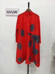 An Elegant Stand Collar Pleated Dress with red long sleeves, large black polka dots, and a tied sash hangs on a wooden hanger against a white wall beside a sign reading GVUW.