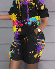 A woman wears a black two-piece set featuring a colorful paint splatter print.
