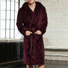 A man wears a long-sleeved, hooded, plush burgundy bathrobe with two front pockets.