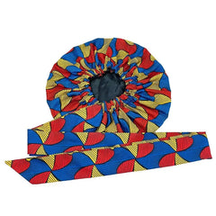 An extra large satin sleep bonnet featuring a colorful African geometric print and a long tie band.