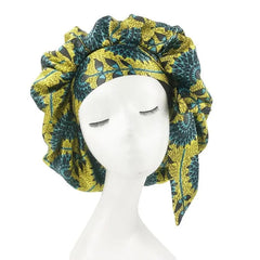 A woman's satin sleep bonnet featuring a yellow and teal African-inspired floral print.