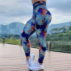 A woman wears high-waisted, ankle-length leggings featuring a colorful, digital tie-dye print.