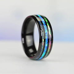A black tungsten wedding band featuring a central inlay of blue opal and abalone shell.