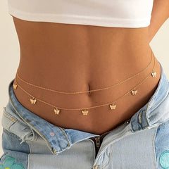 A close-up of a woman's waist features the Fashion Classic Cute Butterfly Waist Chain—simple, thin gold body jewelry with butterfly charms—styled with light blue jeans and a white crop top for a summer-ready look.