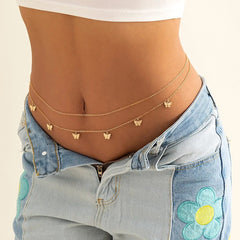 She wears low-rise blue jeans, a white crop top, and gold waist chains adorned with butterfly charms—the Fashion Classic Cute Butterfly Waist Chain—adding a boho touch to her summer vacation look.