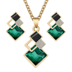 A gold-tone jewelry set featuring a necklace and earrings with geometric green and black crystals.