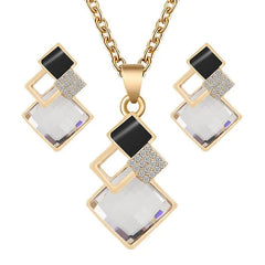 A gold-tone jewelry set featuring a necklace and earrings with geometric crystal and black accents.