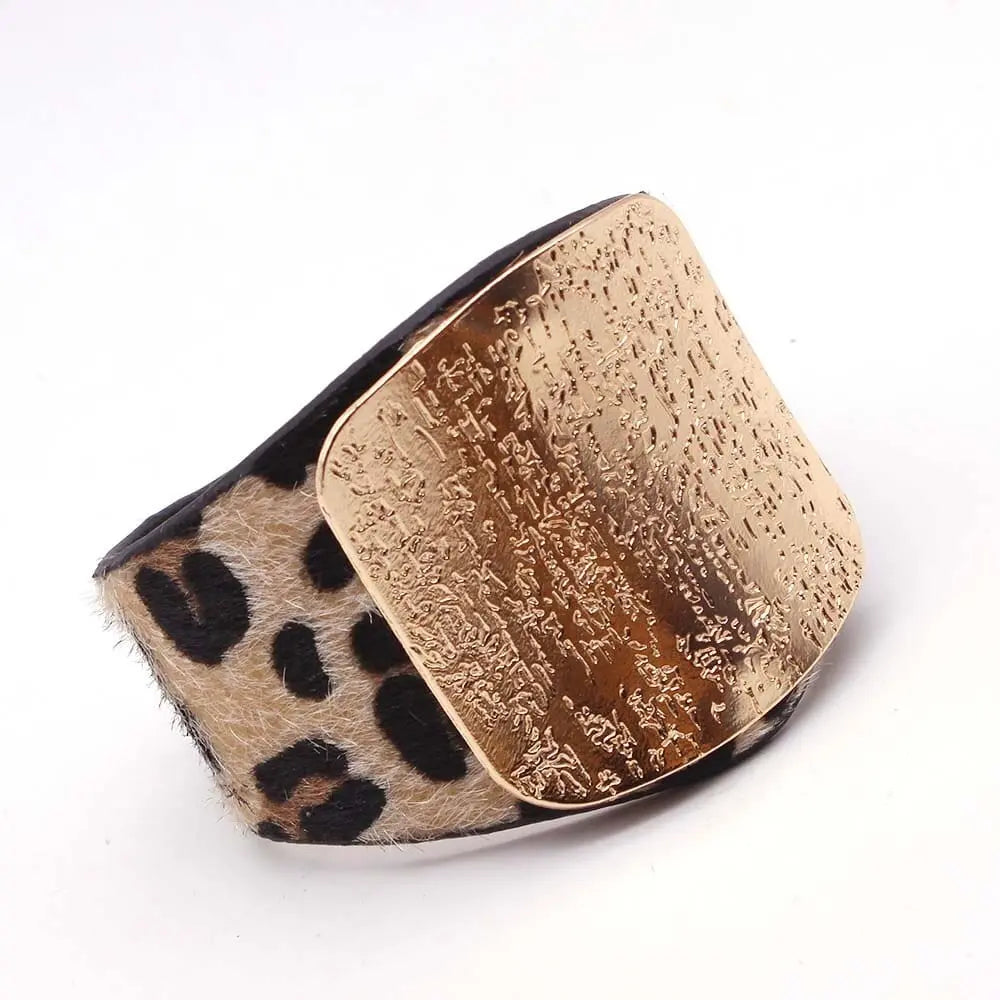 The Fashion Leopard Leather Bracelet for Women features a wide leopard print band and a textured gold-toned V-shaped plate, creating a stylish all-match charm cuff displayed on a white background.