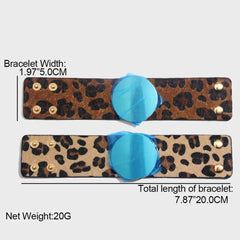 Two Fashion Leopard Leather Bracelets for women are shown horizontally, each with a blue circular centerpiece and gold snap buttons. Each cuff is 1.97 inches (5 cm) wide and 7.87 inches (20 cm) long.