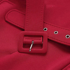 A close-up of a red fabric belt with a matching rectangular buckle and silver metal eyelets.