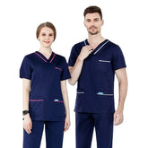 A man and a woman wearing matching navy blue medical scrub sets with contrasting trim.