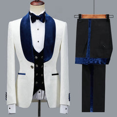 The Floral Jacket Men Suit features a slim fit white jacket with navy blue velvet lapels, a matching blue velvet bow tie and buttons, black waistcoat, and black trousers with blue velvet side stripes—perfect for weddings or parties.