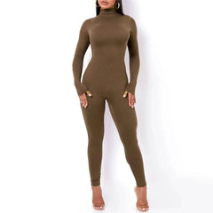 A woman wears a long-sleeved, high-neck olive green jumpsuit made of a tight, stretchy fabric.
