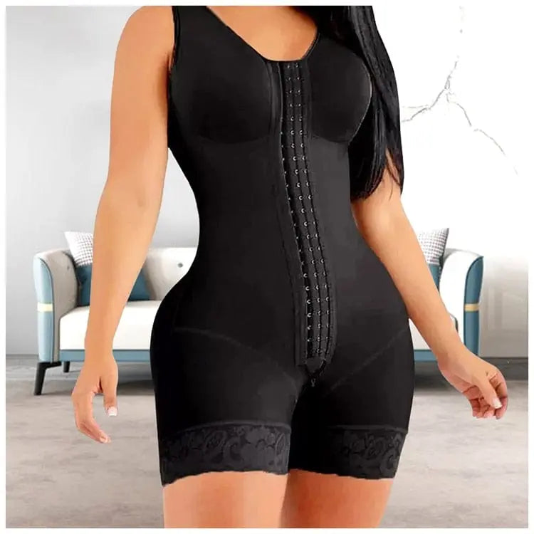 A woman wears the Full Body Shapewear Compression Girdle Fajas Colombian Tummy Control Bodysuit, a black sleeveless shaper with lace-trimmed shorts and front hook closure, standing indoors near a sofa with pillows.