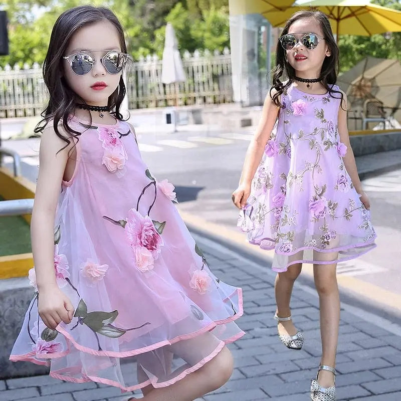 Two girls in sleeveless Girls Flower Dress Chiffon Beach Dresses, one pink and one lavender, walk outside on a sunny day. Both wear sunglasses and have long hair. Perfect floral outfits for ages 6-14.