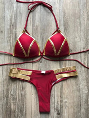 A maroon bikini set featuring gold metallic trim on the triangle top and double-strap bottoms.