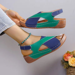 A pair of green and blue leather wedge sandals with an open toe and adjustable back strap.