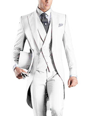 A man wears a slim-fit white three-piece tuxedo with a peaked lapel and a patterned tie.