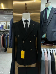 A black double-breasted slim fit suit jacket with gold buttons on a mannequin.
