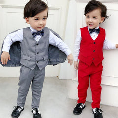 Two young boys wearing formal three-piece suits with polka dot bow ties in grey and red.