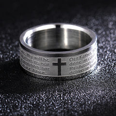 A silver-toned stainless steel ring engraved with the Lord's Prayer and a central black cross.