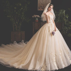 A strapless champagne-colored wedding dress with a sweetheart neckline and an ornate lace train.