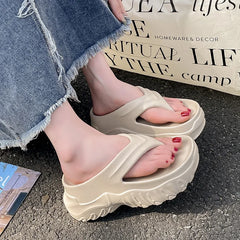 A pair of beige platform flip-flops with a thick, chunky sole worn on a person's feet.