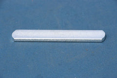 A single rectangular metal weight bar with rounded ends resting on a blue surface.
