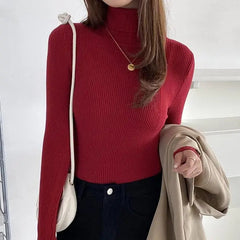 A woman wears a slim-fit, long-sleeved red ribbed turtleneck sweater.