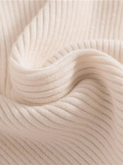 A close-up view of a soft, cream-colored ribbed knit turtleneck sweater.