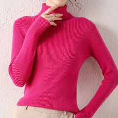 A woman wears a bright pink, slim-fit ribbed turtleneck sweater with long sleeves.