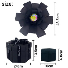 The Hexagon Explosion Box Scrapbook Album is a black hexagonal gift box with a ribbon, opening to reveal petal-like layers and a colorful artificial rose—ideal for DIY scrapbooks or surprise gifts. Size: 24x13.5x10 cm (closed), 48.5 cm (open).