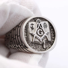 A sterling silver Masonic ring featuring a Bible, square and compass, and brickwork pattern.