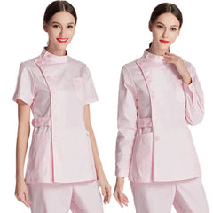 A woman models a light pink medical scrub uniform with a button-up tunic and matching trousers.