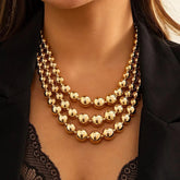 A woman wears a three-layered gold-tone chunky ball choker necklace.