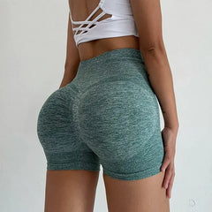 A woman wears high-waisted, green, textured athletic shorts with a hip-lifting design.