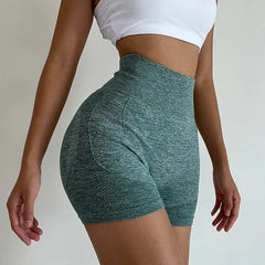 A person wears high-waisted, green marled compression shorts with a textured hip-lifting design.