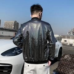 A man wears a silver, diamond-patterned bomber jacket with a stand collar and ribbed cuffs.