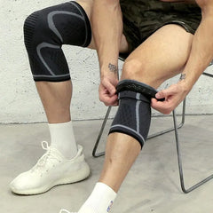 A person wearing a grey and black compression knee sleeve while pulling on a matching one.