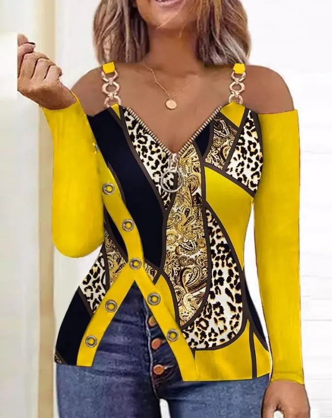 A long-sleeve cold shoulder top featuring a yellow, black, and leopard print with a front zipper.