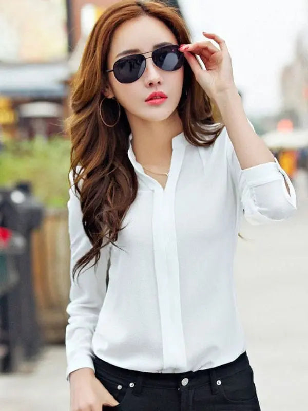A woman wears a long-sleeved white slim-fit chiffon blouse with a V-neckline.